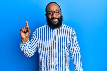 Naklejka premium Young african american man wearing business style smiling with an idea or question pointing finger up with happy face, number one