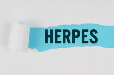 In the middle of a white sheet of paper, a tear is made under which, on a blue background, the inscription - HERPES