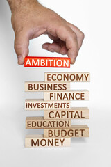 Businessman hand sets on a tower with business words red wooden block with the inscription - AMBITION