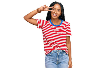 Beautiful hispanic woman wearing casual clothes doing peace symbol with fingers over face, smiling cheerful showing victory