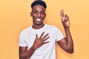 Young african american man wearing casual clothes smiling swearing with hand on chest and fingers...
