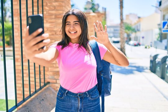 Young latin student girl doing video call using smartphone at university campus.