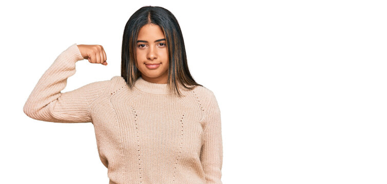 Young latin girl wearing wool winter sweater strong person showing arm muscle, confident and proud of power