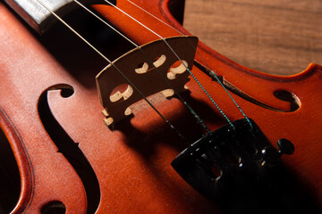 Violin, details of a beautiful violin on wooden surface and black background, low key selective...