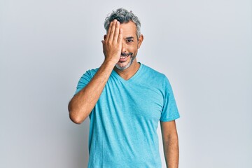 Middle age grey-haired man wearing casual clothes covering one eye with hand, confident smile on...