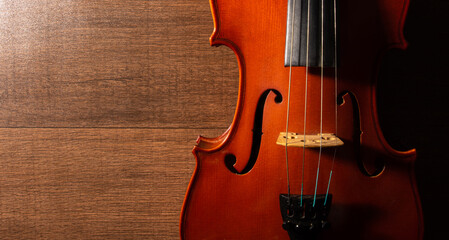 Violin, details of a beautiful violin on wooden surface and black background, low key selective focus portrait.