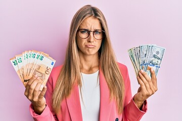 Young blonde woman wearing business style holding dollars and euros banknotes depressed and worry for distress, crying angry and afraid. sad expression.
