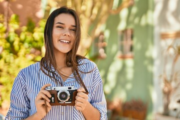 Young hispanic tourist girl smiling happy using camera at the park.