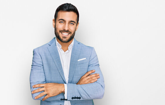 Young hispanic man wearing business jacket happy face smiling with crossed arms looking at the camera. positive person.