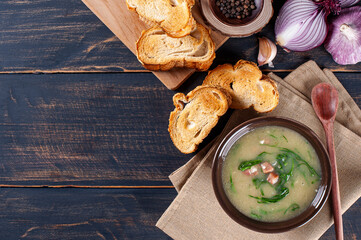 Popular dish of Portuguese cuisine called Caldo Verde. Made with potatoes, bacon, pepperoni sausage and kale. Top view. Copy space