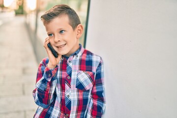Adorable caucasian boy smiling happy talking on the smartphone at the city.