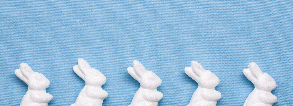 White Styrofoam Glittered Bunnies Border On A Light Baby Blue Fabric Background