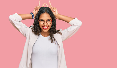Naklejka premium Young african american girl wearing business clothes posing funny and crazy with fingers on head as bunny ears, smiling cheerful