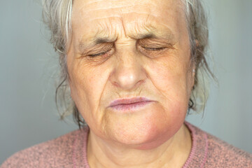 Depressed mature woman isolated on grey studio background touch cheek suffering from tooth pain