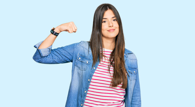 Young brunette woman wearing casual clothes strong person showing arm muscle, confident and proud of power