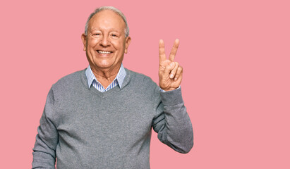 Senior caucasian man wearing casual clothes smiling with happy face winking at the camera doing victory sign. number two. - obrazy, fototapety, plakaty