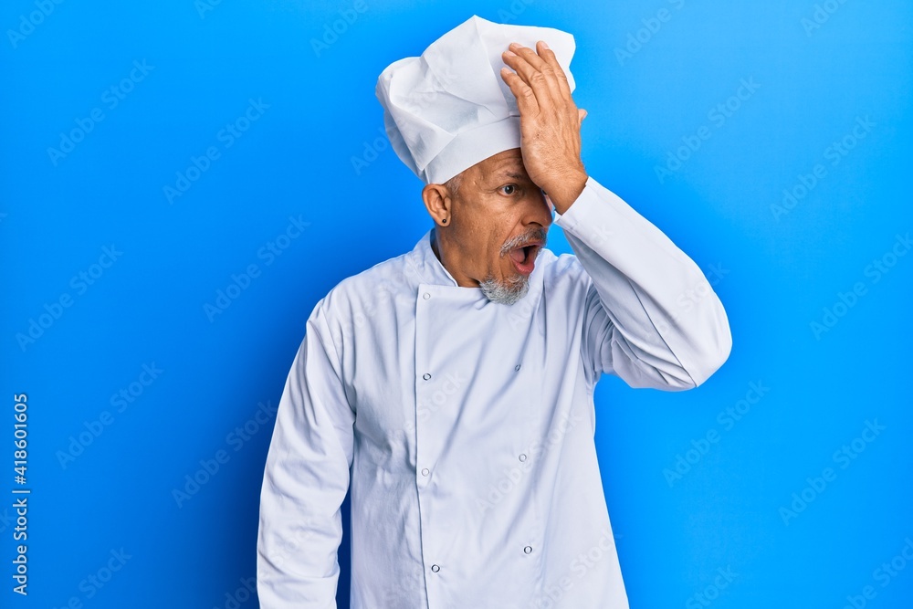 Sticker Middle age grey-haired man wearing professional cook uniform and hat surprised with hand on head for mistake, remember error. forgot, bad memory concept.