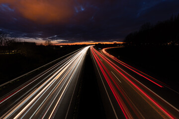 Fototapeta na wymiar Autobahn bei Nacht mit fahrenden Autos. Langzeitbelichtung mit dramatischen Himmel 