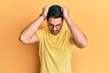 Fototapeta na wymiar Young hispanic man wearing casual clothes and glasses suffering from headache desperate and stressed because pain and migraine. hands on head.