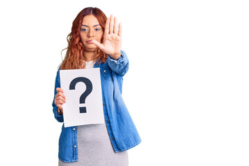 Young latin woman holding question mark with open hand doing stop sign with serious and confident expression, defense gesture