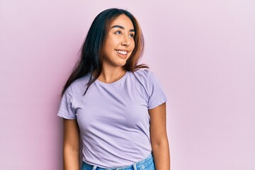 Fototapeta premium Young latin woman wearing casual clothes looking to side, relax profile pose with natural face and confident smile.