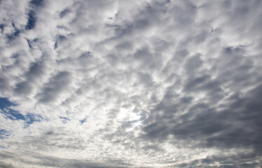 White and grey cotton-textured clouds spread across a blue sky to the horizon
