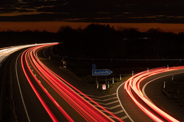 Autobahn, Kreuzung bei Nacht mit fahrenden Autos. Langzeitbelichtung mit dramatischen Himmel