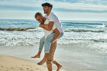 Lovely gay couple on piggyback ride at the beach. - Powered by Adobe