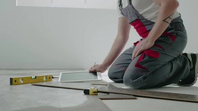 Employee draws in tablet and takes measure tape on floor