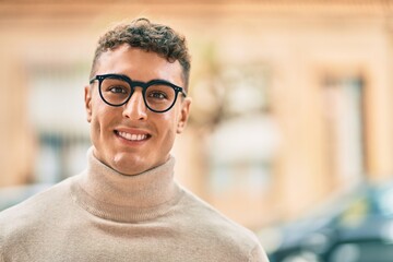 Young hispanic man smiling happy wearing glasses at the city.