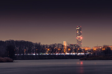 Sky Tower Wroclaw and the Milenijny Bridge over the Odra River visible in the evening from the shore.