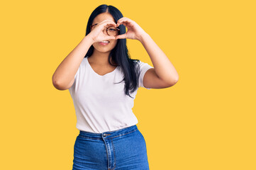 Young beautiful asian girl wearing casual clothes and glasses doing heart shape with hand and fingers smiling looking through sign