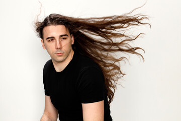 Attractive young guy with very long curly hair is posing in studio. Style, trends, fashion concept.