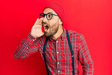 Handsome man with beard wearing hipster elegant look shouting and screaming loud to side with hand on mouth. communication concept.