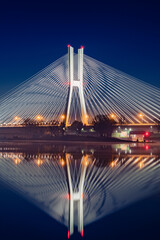 Wroclaw Redzinski Bridge over the Odra River, the illuminated bridge is reflected in the water.