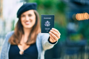 Young latin woman wearing french style holding usa passport at the city.