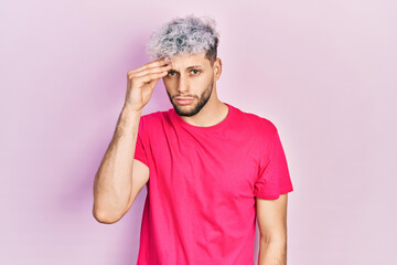 Young hispanic man with modern dyed hair wearing casual pink t shirt worried and stressed about a problem with hand on forehead, nervous and anxious for crisis