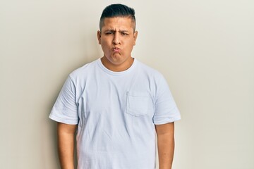 Young latin man wearing casual white t shirt depressed and worry for distress, crying angry and afraid. sad expression.