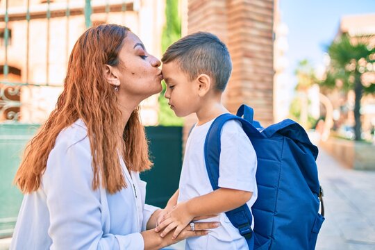 Adorable latin student boy and mom kissing at the city.