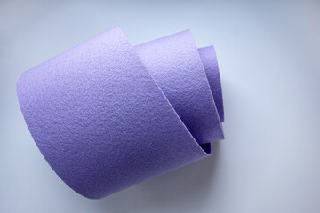 A rolled piece of purple felt fabric on a white background