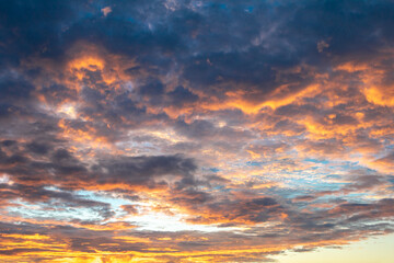 Orange and White cotton-textured clouds spread across a blue sky to the horizon