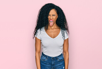 Middle age african american woman wearing casual white t shirt sticking tongue out happy with funny expression. emotion concept.
