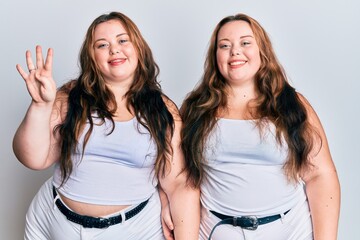 Plus size caucasian sisters woman wearing casual white clothes showing and pointing up with fingers number four while smiling confident and happy.