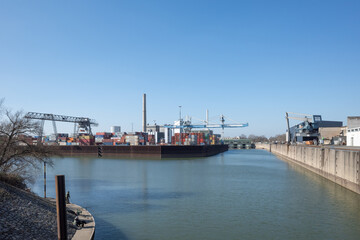 Outdoor sunny view at Düsseldorf-Hafen with Shipyard cranes or portal cranes, harbour port and stack of containers against blue sky.