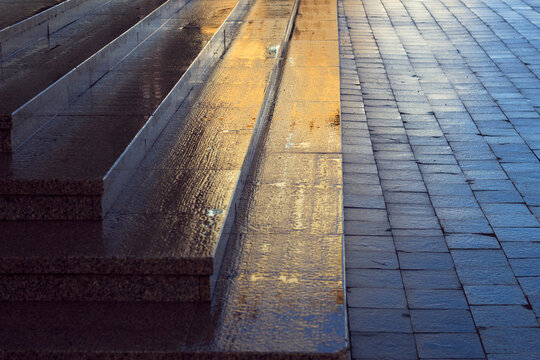 wet red granite stairs and city pavement pattern -  textured background with sunlight and reflections, city parallel lines with light and cold shadow