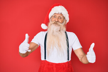 Fototapeta na wymiar Old senior man with grey hair and long beard wearing white t-shirt and santa claus costume success sign doing positive gesture with hand, thumbs up smiling and happy. cheerful expression.