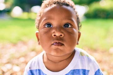 Adorable african american toddler sitting on the grass at the park.