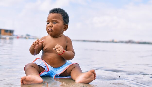 Adorable african american toddler sitting at the beach.