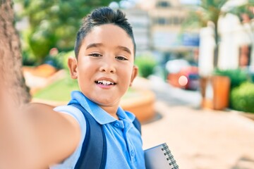 Adorable student boy smiling happy making selfie by the camera at street of city.