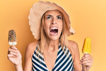 Beautiful blonde woman wearing summer style holding ice cream angry and mad screaming frustrated and furious, shouting with anger looking up.